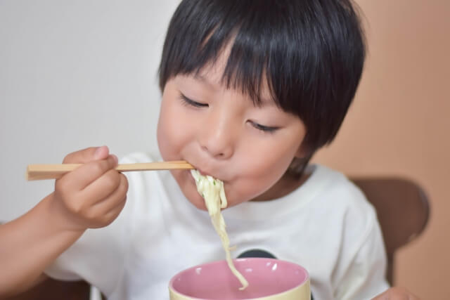 箸で食事をする男の子